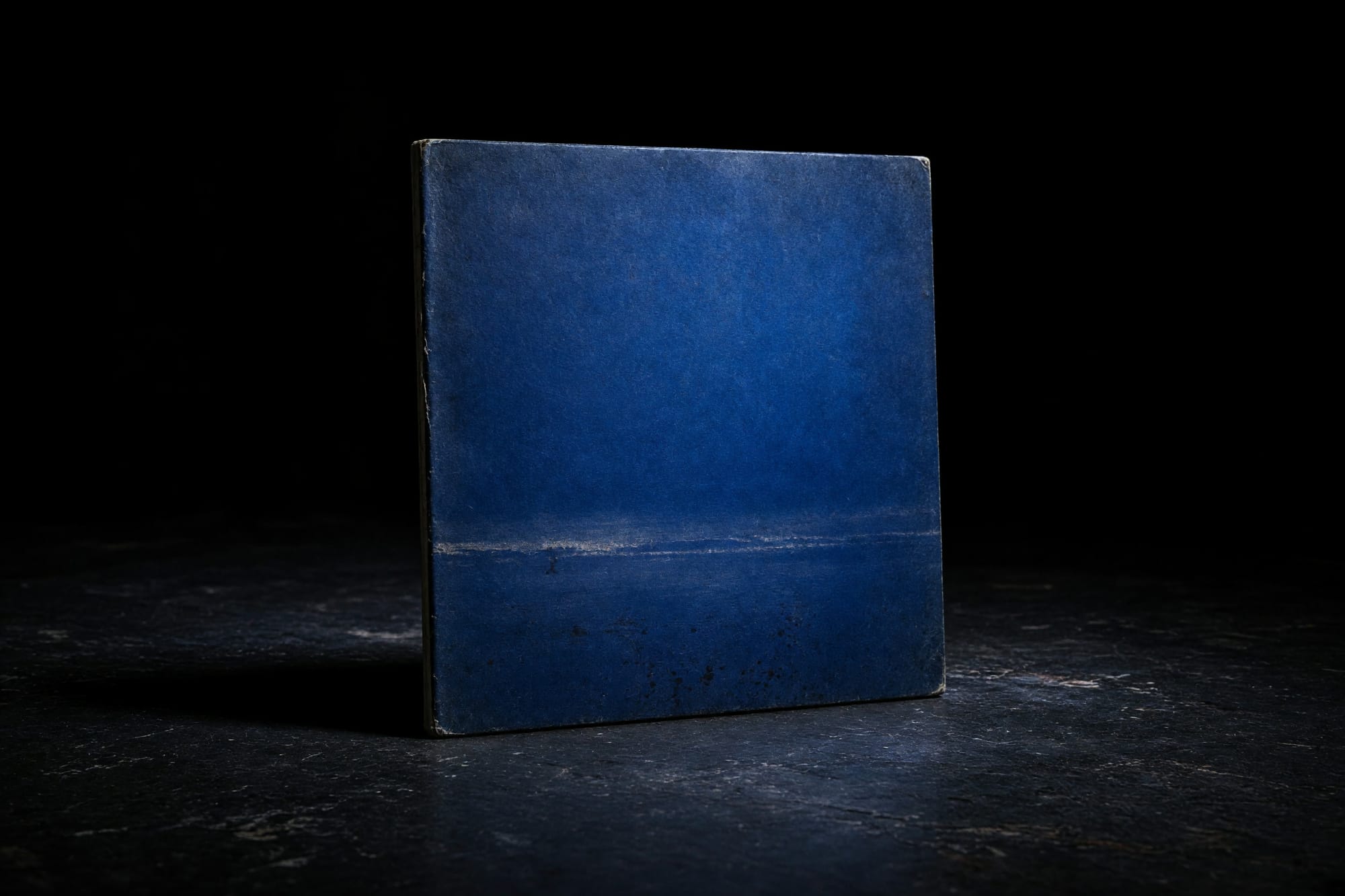The finished sleeve face propped on a dark floor, reduced to a blue field